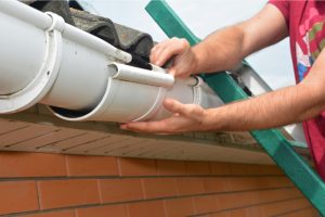 Gutter pipeline installation by a worker on a ladder.