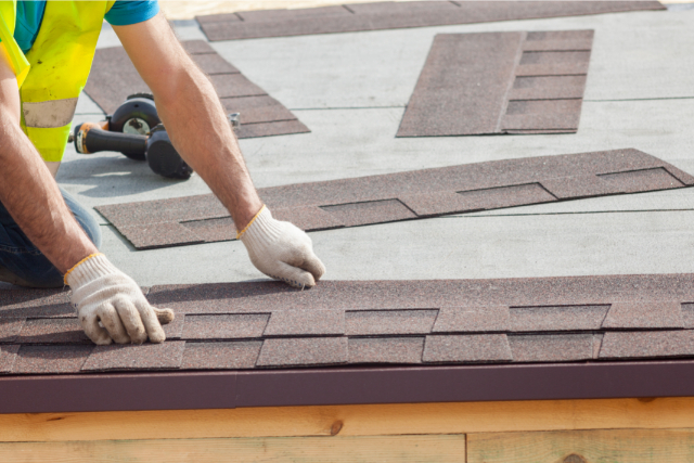 New roof installation by worker with gloves on.